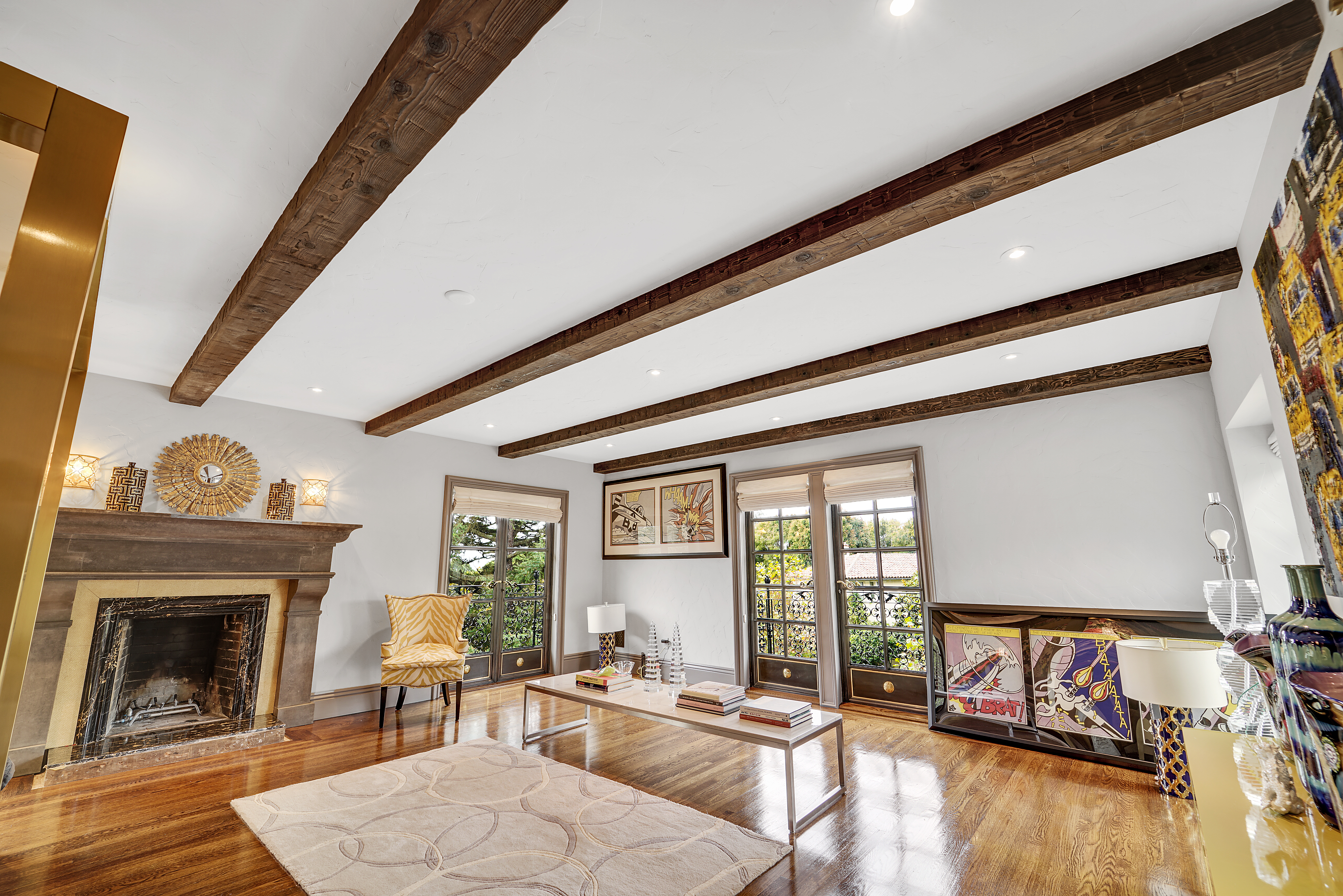 Hand Hewn Faux Wood Beams in Caramel in a bright room with a fireplace and polished wood floors.